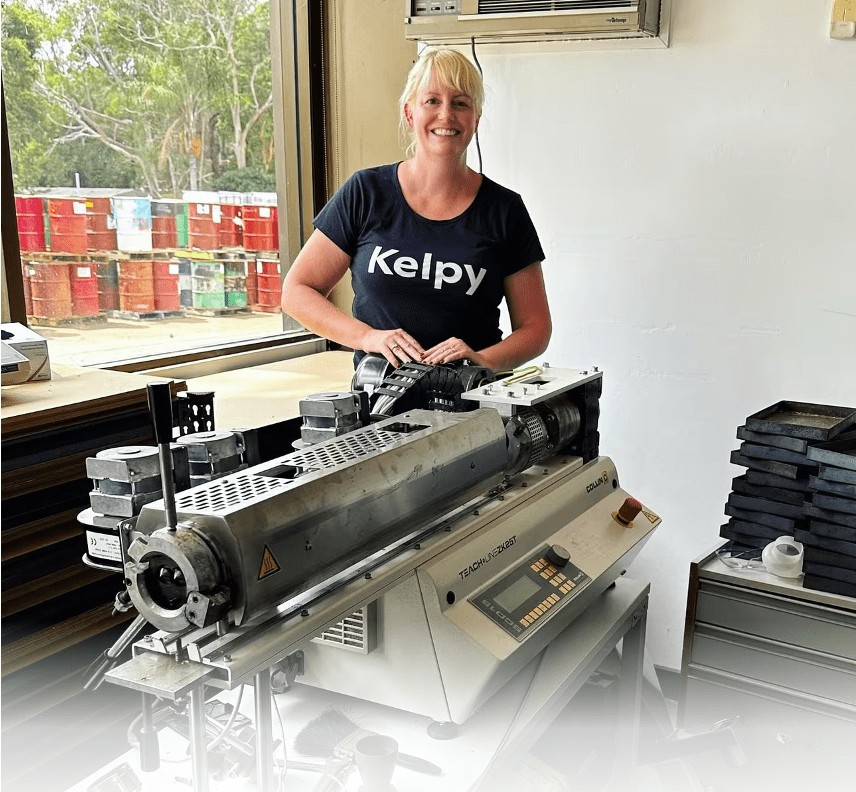 Photograph of Kelpy Founder and CEO Fionnuala Quin next to machinery in her factory making plastic from kelp, a sea weed.  Credit https://thefishsite.com/articles/kelpy-launches-seaweed-based-bioplastic-pellets